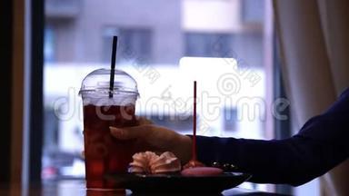 年轻迷人的女人坐在咖啡馆里喝一杯清爽的饮料。